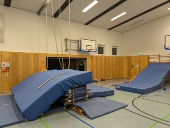 Ein großer Weichbodenberg mit Kletterseilen steht aufgebaut in der Hallenmitte.